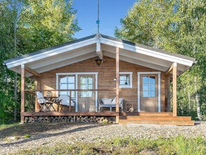 Una baita di legno con portico, due finestre e una porta.