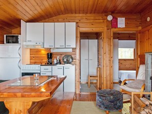 A compact kitchen with white cabinets, a coffee maker, and a microwave. There is a wooden dining table with a glass top and a chair. - Lahdenpohja, vaikon loma 7 by Interhome (Kaavi)