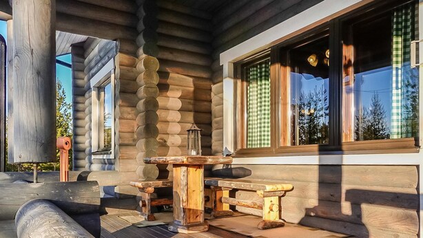 A log cabin with a wooden deck, a table, and benches. - Inarinlahti by Interhome (Inari)