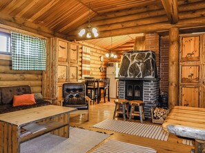 Ein rustikales Blockhaus-Interieur mit Kamin, Holzmöbeln und einer gemütlichen Sitzecke.