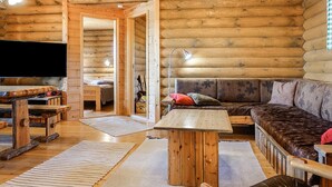 A log cabin interior with a wooden floor, a sofa, a table, and a TV. - Inarinlahti by Interhome (Inari)