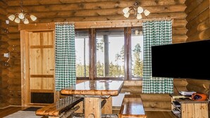 A wooden cabin interior with a wooden table and benches, a television, and checkered curtains. - Inarinlahti by Interhome (Inari)