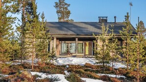 A log cabin with a large window and a chimney, surrounded by snow and trees. - Inarinlahti by Interhome (Inari)