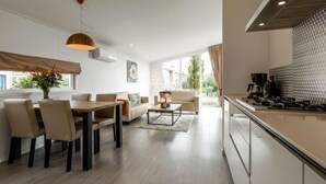 A modern kitchen with a large island, a dining area with a wooden table and chairs, and a living area with a sofa and coffee table.