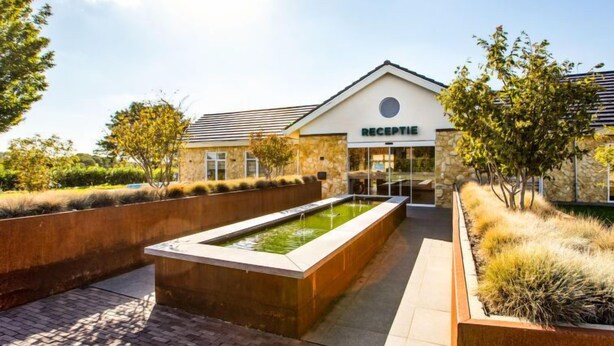 A reception area with a stone facade, a water feature, and a paved walkway.
