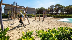 A sandy beach with a wooden swing set and a slide.