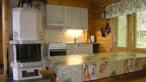 Eine gemütliche Küchenzeile im Blockhausstil mit einer hölzernen Bank, weißen Schränken und einem Kamin.