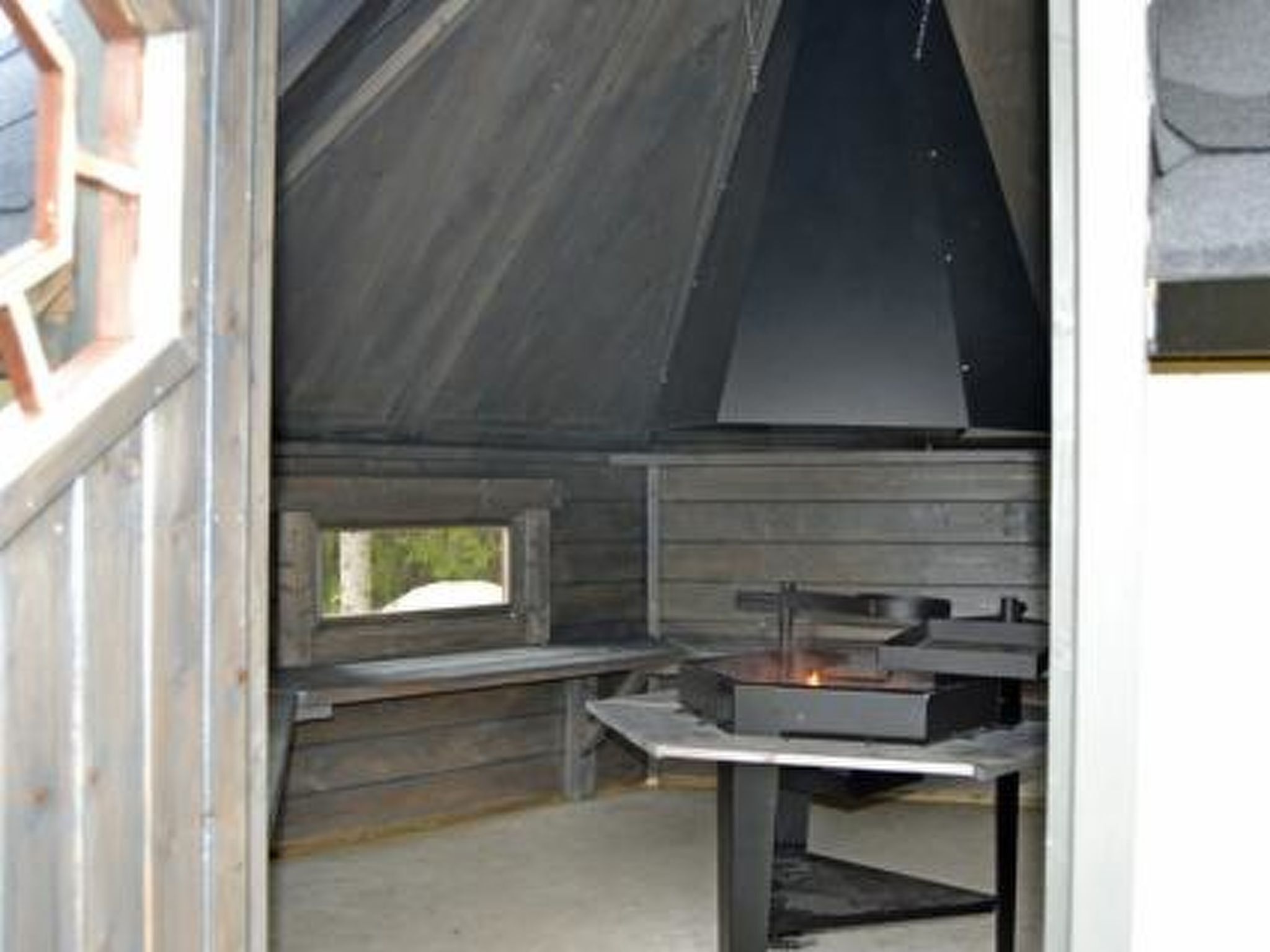 L’intérieur d’un chalet en bois rustique, avec une cheminée, un banc et une petite fenêtre.