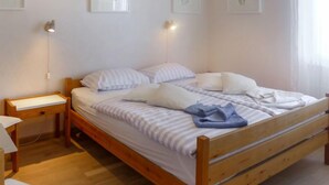 A wooden bed with white and striped bedding, a bedside table, and a nightstand. - Noisette by Interhome (Le Mont-Pèlerin)