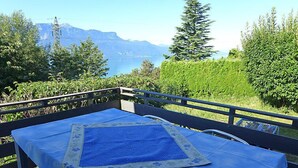 A balcony with a table covered in a blue tablecloth, overlooking a lake and mountains. - Noisette by Interhome (Le Mont-Pèlerin)