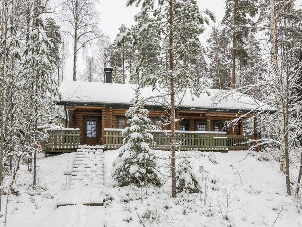 A log cabin surrounded by snow-covered trees. - Kanervakallio by Interhome (Multia)