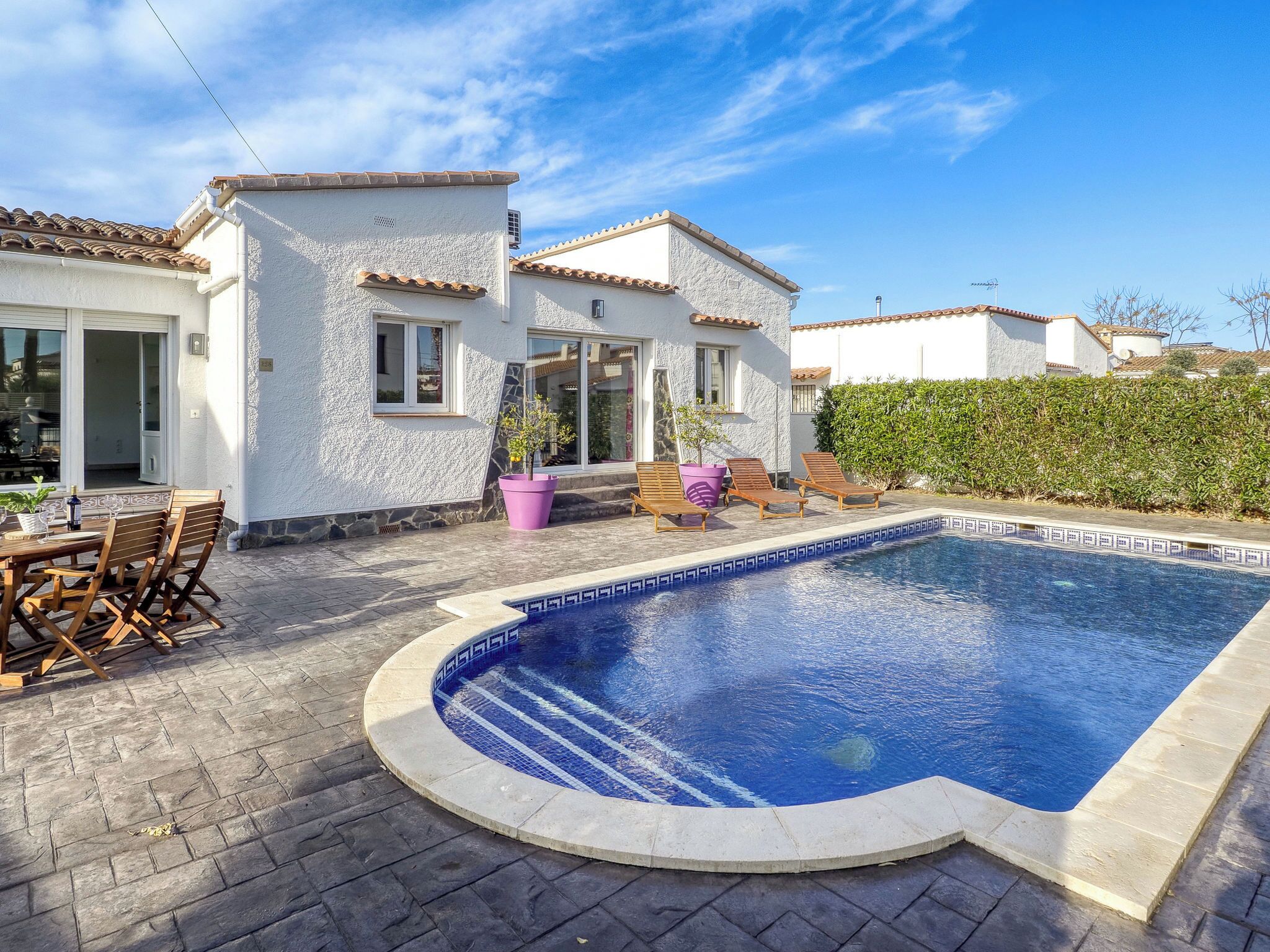 Une propriété résidentielle dotée d’une piscine, de mobilier de jardin et d’une façade blanche.
