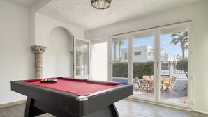 A pool table in a room with a large glass door leading to an outdoor patio area. - Montgri by Interhome (Empuriabrava)
