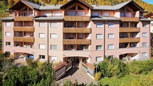 A multi-story hotel with balconies, a central entrance, and a mountainous backdrop. - Chesa Sur Val 22 by Interhome (St. Moritz)