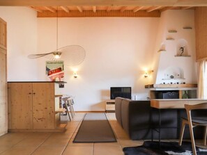 Una cocina moderna con armarios de madera, un comedor con sofá y televisor.