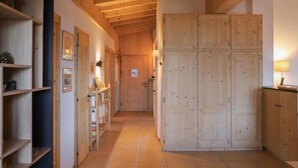 A hallway with wooden shelving, a tiled floor, and a wooden door at the end. - Ermitage 11 by Interhome (Villars)