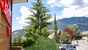 Vista di un parcheggio con auto, un edificio con un cartello rosso e una montagna sullo sfondo.