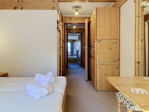 A hotel room with a bed, a table with playing cards, and a wooden wardrobe.
