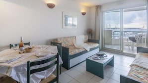 A modern hotel room with a balcony, a dining area, and a sofa. - Apartment L'Open by Interhome (Fréjus)
