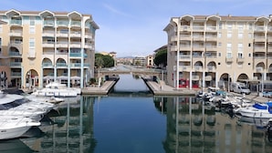 A marina with boats docked, a canal, and a row of multi-story buildings with balconies. - Apartment L'Open by Interhome (Fréjus)