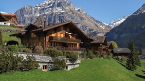 Un edificio de estilo chalé con balcón, con montañas al fondo.