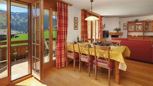 Un comedor con una mesa preparada para cuatro personas, un sofá y un televisor.