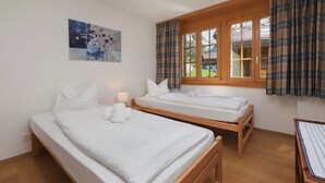 Una habitación con dos camas de madera, un cuadro en la pared y una ventana con cortinas.