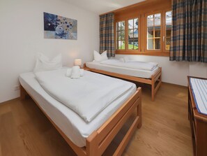 Ein Zimmer mit zwei Holzbettgestellen, einem Bild an der Wand und einem Fenster mit Vorhängen.