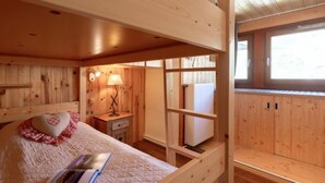 Ein Schlafraum mit Etagenbetten, einem Holzkopfteil, einem Nachttisch mit Lampe und einem Fenster mit Blick.