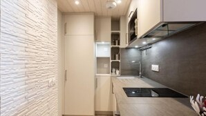 Eine moderne Küche mit einer Holzvertäfelung, eingebauten Schränken und einer Edelstahl-Spritzschutzwand.