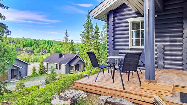 Hirsihökkelissä on terassi, ulkona oleva oleskelualue ja näkymä metsäiselle alueelle.