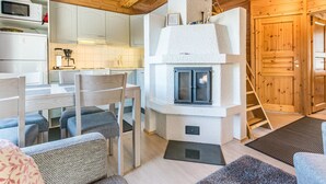 Tunnelmallinen mökin sisustus, jossa on ruokailutila, keittiö ja takka.