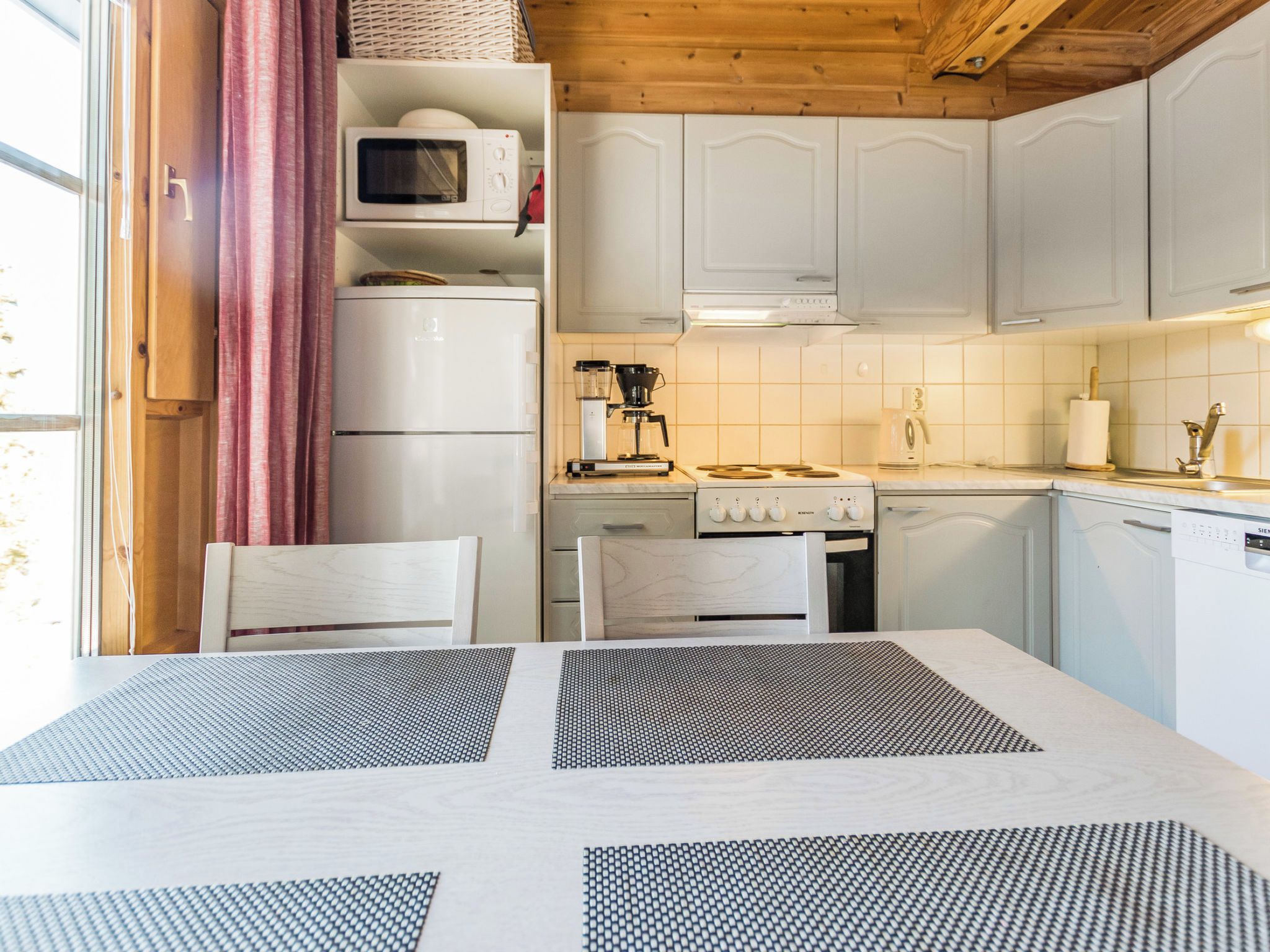 A kitchen with white cabinets, a microwave, a coffee maker, and a stove.