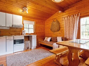 A cabin interior with a kitchen, dining area, and seating space. - Koskimökki, vaikon loma 3 by Interhome (Kaavi)