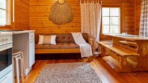 A cozy cabin interior with a wooden interior, a sofa, a dining table, and a kitchenette. - Koskimökki, vaikon loma 3 by Interhome (Kaavi)