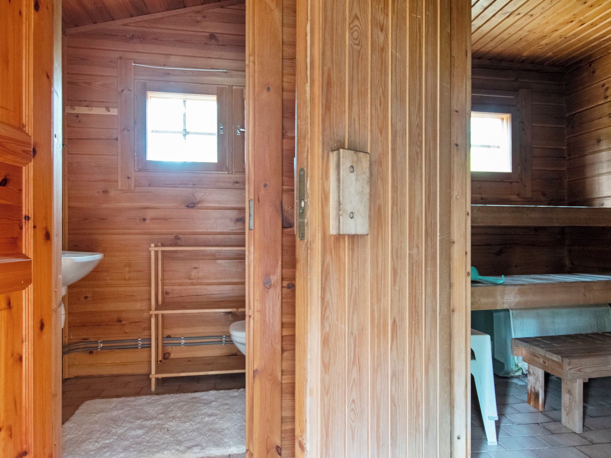 A wooden cabin interior with a window, a sink, and a bench.