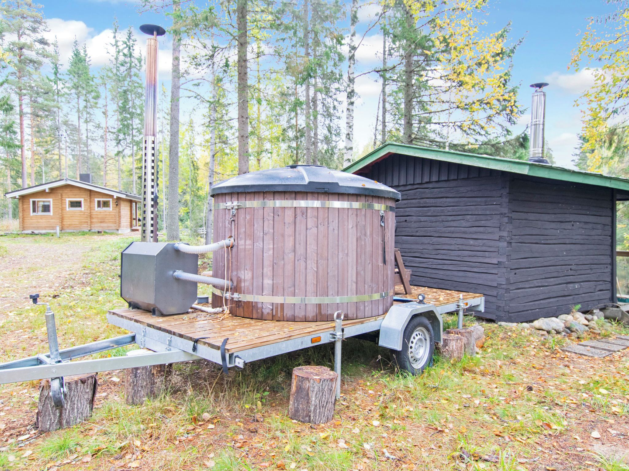 Een verplaatsbare sauna op een aanhanger, met een houten huisje op de achtergrond.