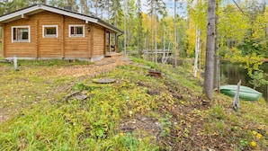A wooden cabin with a porch, surrounded by a forest and a lake. - Koskimökki, vaikon loma 3 by Interhome (Kaavi)
