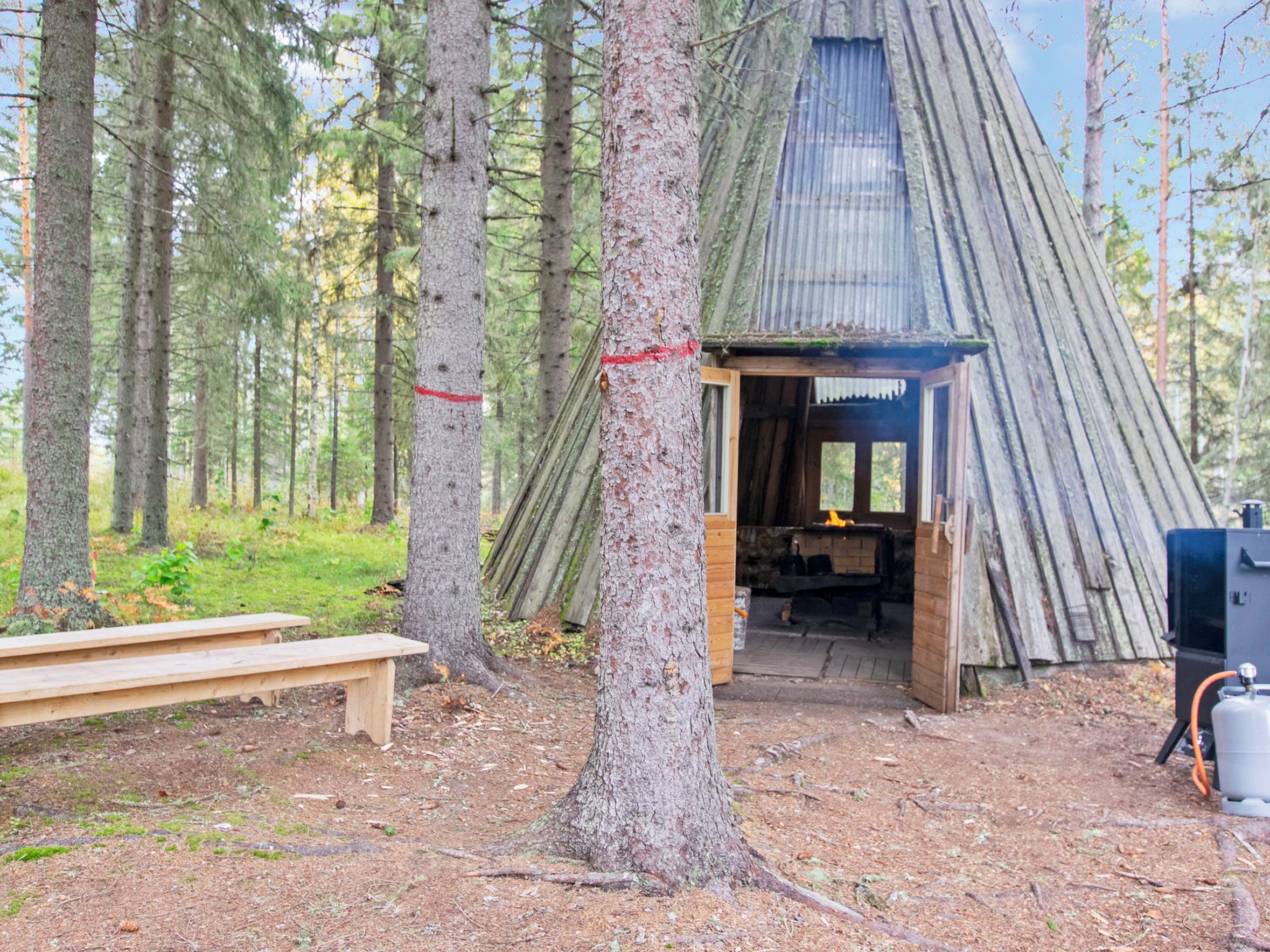 Un chalet rustique avec une porte en bois, un banc et une cheminée.