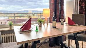 A dining table with a bottle of wine, a glass, and a red napkin. There is a potted plant and a lamp on the table. - Braubach (B715) by Interhome (Lahnstein (Koblenz))