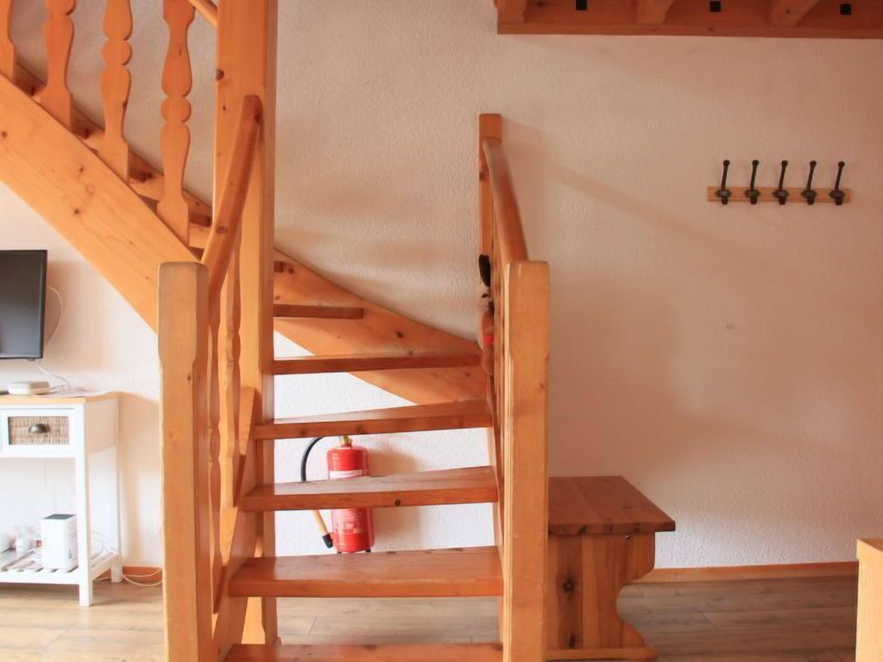 Un escalier en bois avec un extincteur sur la plateforme.