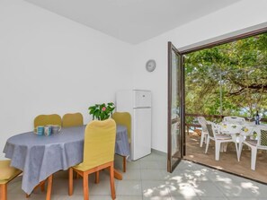 Un comedor con una mesa y sillas, una planta en maceta y un refrigerador.