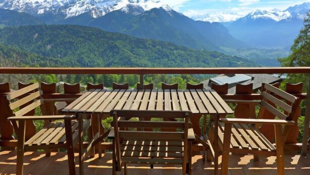 A wooden deck with a table and chairs overlooking a mountainous landscape. - Les Aiguilles d'Argent 10 by Interhome (Villars)