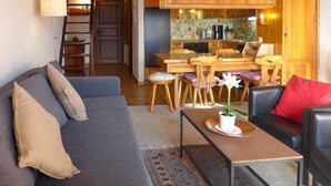 A cozy living room with a sofa, a coffee table, and a dining area with wooden chairs and a table. - Les Aiguilles d'Argent 10 by Interhome (Villars)