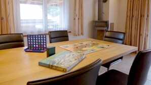 A dining area with a wooden table, chairs, a board game, and a book.