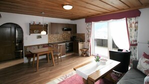 Una cocina acogedora con armarios de madera, una mesa de comedor y un ventanal con cortinas.