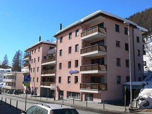 Un hotel a più piani con balconi, un segnale di parcheggio e terreno innevato.
