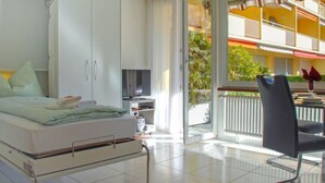 A modern hotel room with a bed, a TV, and a balcony with a dining area. - Residenza Lido Appartment 008 by Interhome (Locarno)