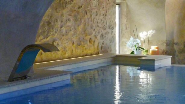 Un área de piscina interior tranquila con una pared de piedra y un pequeño altar con velas y flores.