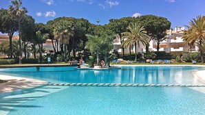 Uma piscina grande e convidativa, com espreguiçadeiras e palmeiras ao fundo.